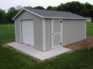 Atlantic shed with metal siding, roll top door and swinging barn door.